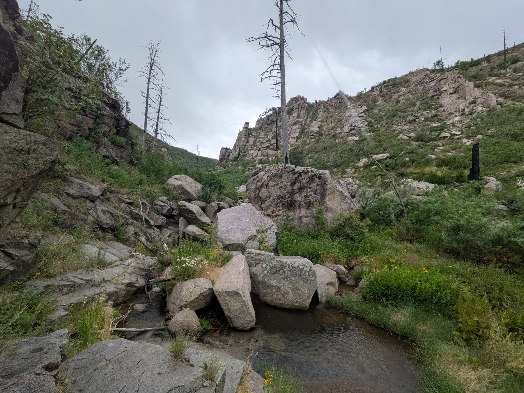 A clear pool below boulders in a rocky mountain canyon